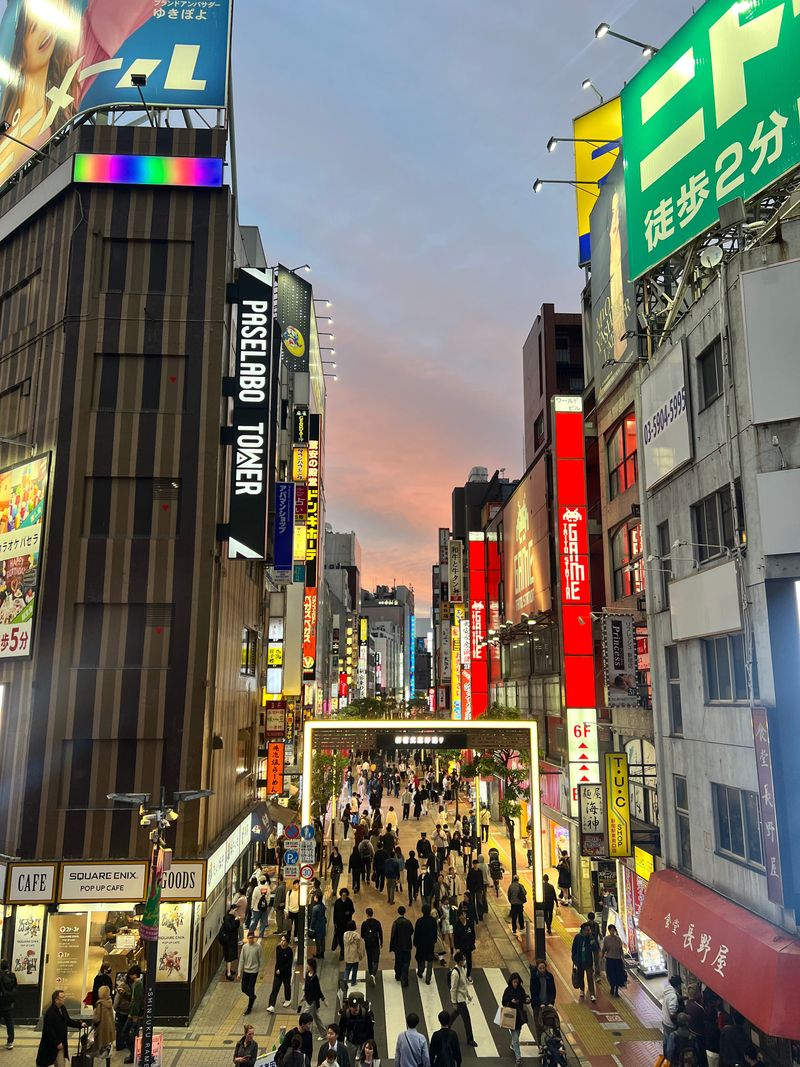A crowded Tokyo shopping street lit by colorful neon signs