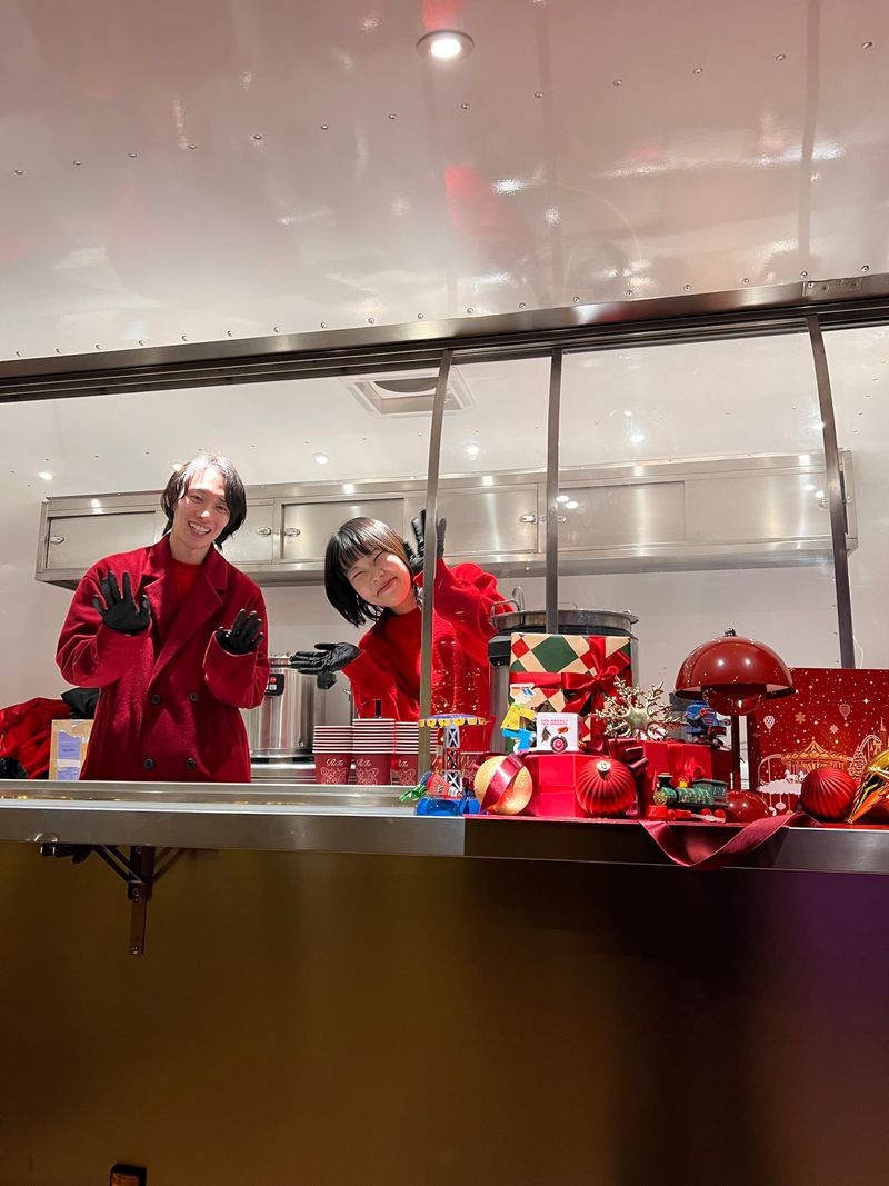 Performers in vivid red costumes seen through a glass window