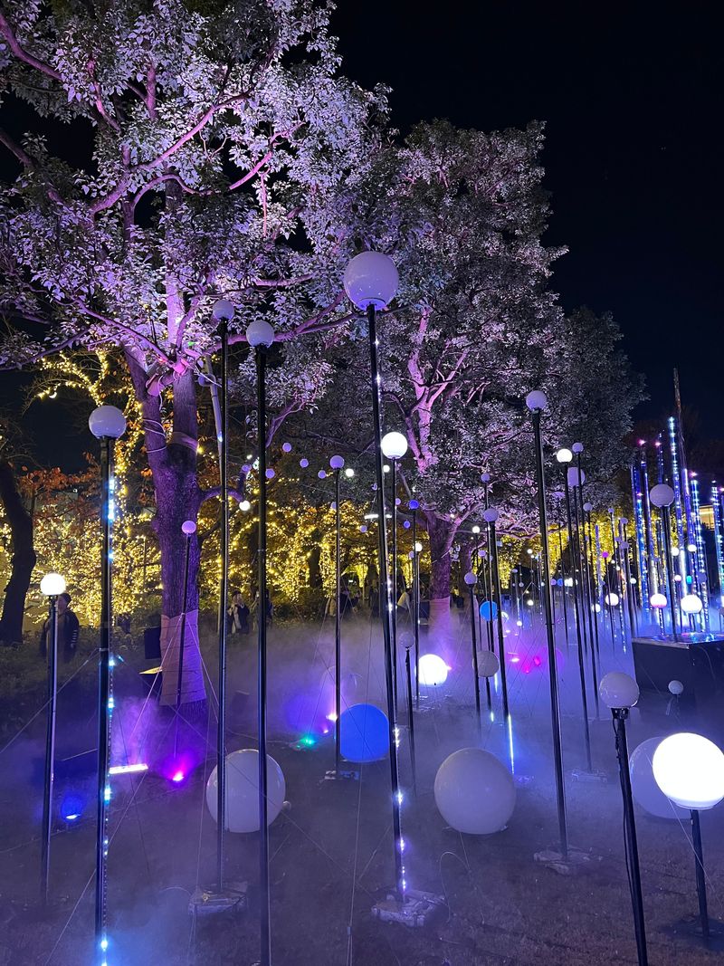 Purple-lit cherry blossoms blooming beside a skyscraper