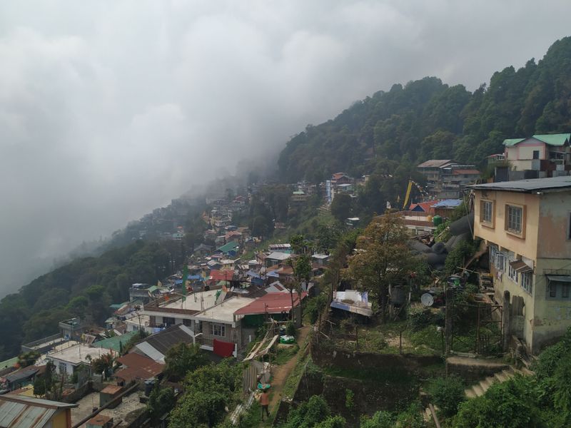 A hillside town of colorful roofs fading into thick mountain fog