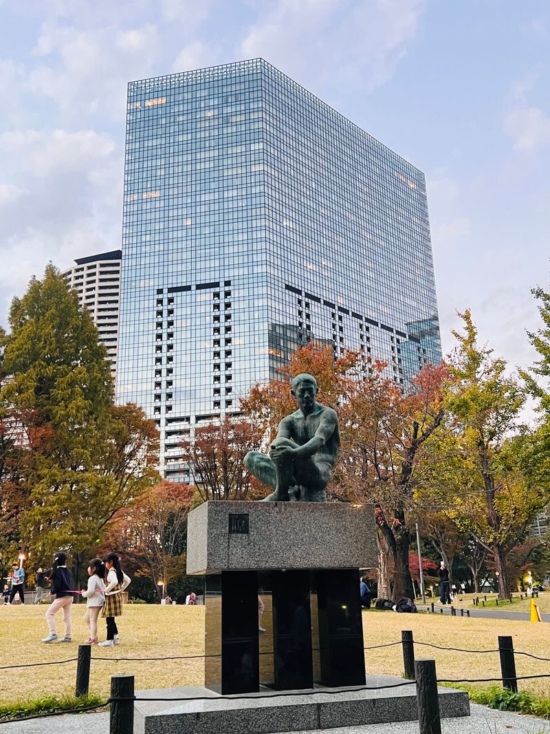 A city plaza and statue in front of a modern glass building