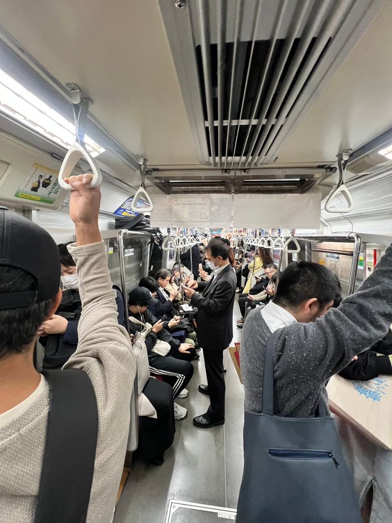 Passengers standing and seated on a crowded subway car