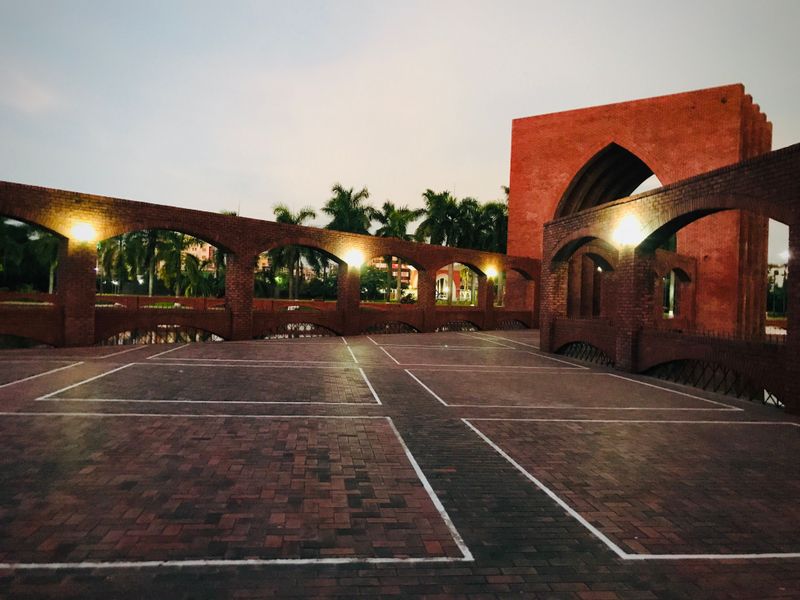 An empty brick courtyard with illuminated arches at dusk