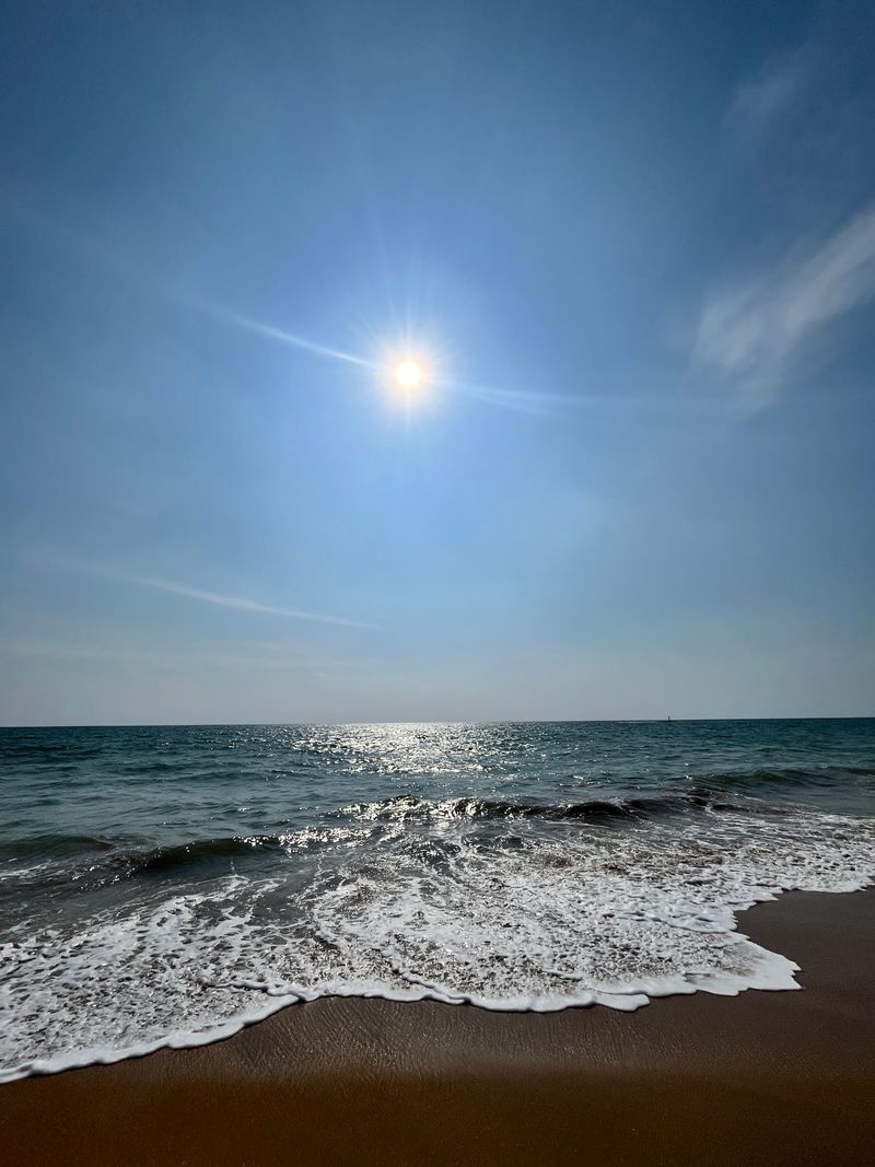 Bright sunlight shimmering across ocean waves near the shore