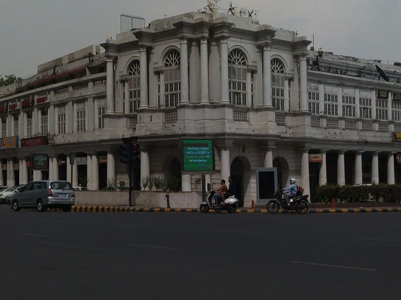 A colonial white corner building with columns beside a busy city intersection