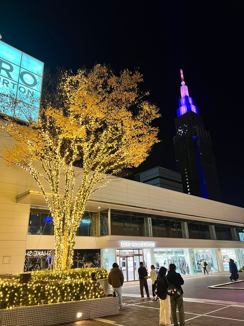 A golden ginkgo tree illuminated beneath an elevated roadway