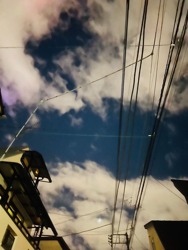 Soft clouds and utility wires crossing a clear blue sky